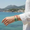Deniz kenarında bilekte görünen kırmızı güneş ve beyaz tilki desenli Kitsura elastik bileklik – QOOP Band kumaş bileklik modeli.
