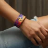 Renkli çita desenli QOOP Band elastik bileklik takan kişinin kolu – modern unisex bileklik lifestyle fotoğrafı